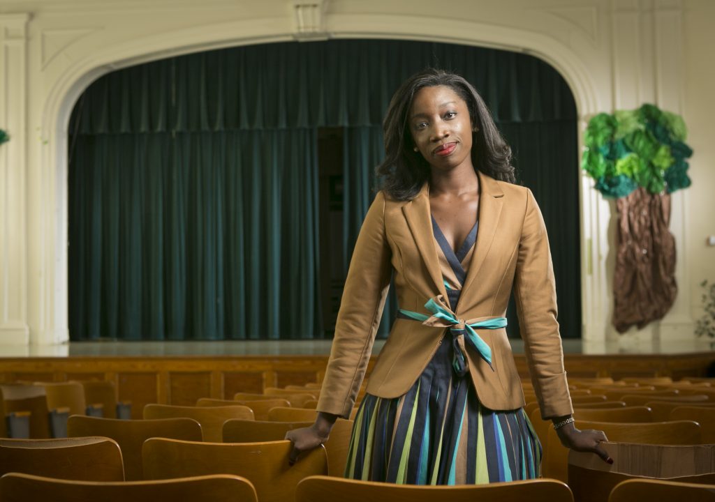 Sally Nuamah, assistant professor in the Sanford School of Public Policy, poses for a photo in the auditorium at E.K. Powe Elementary School in Durham.