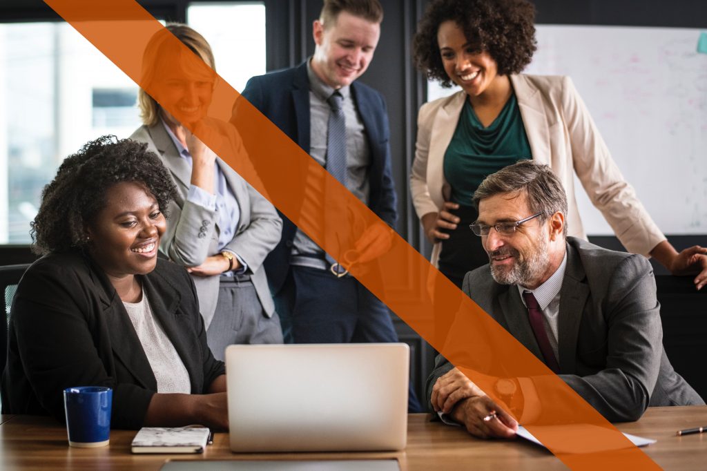 Employees gather around a laptop in a stereotypical stock photo